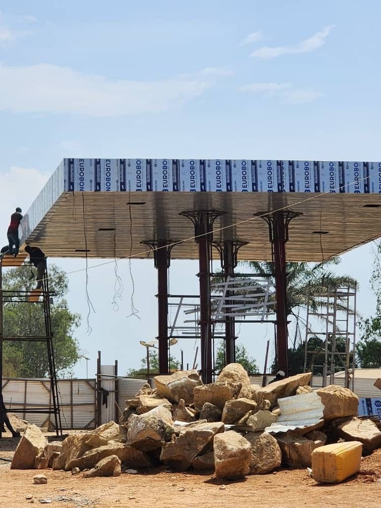 Station canopy under construction with steel columns, soffit, and scaffolding